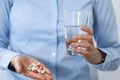 Young unknown woman holding pills and glass of water, closeup of hands.  Medicine and healthcare concept Royalty Free Stock Photo