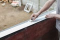 Caucasian male builder clean plastic window with construction knife.