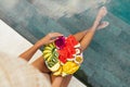 Young unrecognizable woman by the pool with a plate of tropical fruits: watermelon, pineapple, bananas, mangosteen Royalty Free Stock Photo