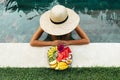 Young unrecognizable woman by the pool with a plate of tropical fruits: watermelon, pineapple, bananas, mangosteen Royalty Free Stock Photo