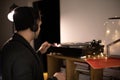 Young unshaven handsome hipster guy push start button on turntable backlit