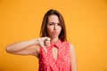 Young upset brunette woman showing thumb down gesture, looking a