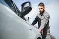 Young upset casual man trying to fix his broken car outdoors. Man waiting for towing service for help car accident on Royalty Free Stock Photo