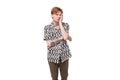 young upset caucasian man with red hair with a tattoo is dressed in a summer black and white shirt on a background with