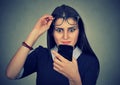 Young upset confused woman with glasses looking at mobile phone Royalty Free Stock Photo