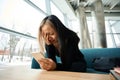 Young upset and crying asian female IT employee using smartphone Royalty Free Stock Photo