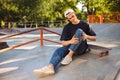 Young upset skater holding his painful leg with skateboard near at skatepark Royalty Free Stock Photo