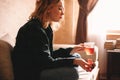 Young woman drinking tea and eating chocolate while sitting on sofa in living room at home Royalty Free Stock Photo