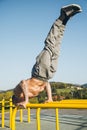 Young urban athlete doing a diagonal handstand on parallel bars at a calisthenics gym