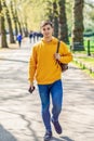 Young urban man using smartphone walking in street in an urban park in London. Royalty Free Stock Photo