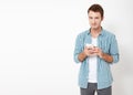 Attractive man with short dark hair chatting or typing text message using cell phone isolated over white background Royalty Free Stock Photo