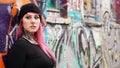 young urban woman leaning against grafitti wall