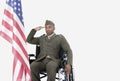 Young US soldier in wheelchair saluting American flag over gray background Royalty Free Stock Photo