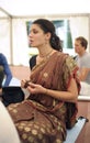 Young Vaishnava woman playing Indian traditional musical instrument for kirtan karatals and singing mantras