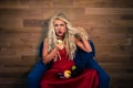 Young vegetarian woman in elegant red dress sits on armchair Royalty Free Stock Photo