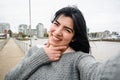 young latin woman laughing making funny selfie portrait with her phone