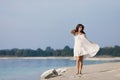 Young very beautiful girl with long hair in a white dress by the lake.