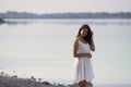 Young very beautiful girl with long hair in a white dress by the lake.