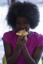 Woman with afro hairstyle eating tasty pizza slice