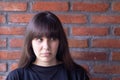 Young very upset brunette woman with bangs wearing a black t-shirt ashamed on brick wall background Royalty Free Stock Photo