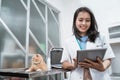 young veterinarian smiling while using digital tablet near a cat sits on the table