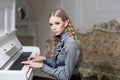 Young Victorian girl in a tender blue dress learning to play piano. Lovely blond with curly hair woman sitting in room