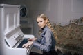 Young Victorian lady in a tender blue dress playing piano. Lovely blond woman sitting in room with vintage furniture Royalty Free Stock Photo