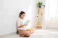 Young Vietnamese girl drinkng tea and reading a book while sitting on the floor Royalty Free Stock Photo