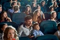 Young viewers watching cartoon and smiling in cinema.