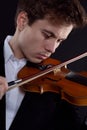 Young violinist playing an old instrument on a dark background, close-up portrait Royalty Free Stock Photo