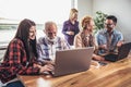 Young volunteers help senior people on the computer.