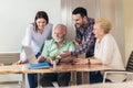 Young volunteers help senior people on the computer.