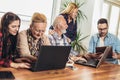 Young volunteers help senior people on the computer.