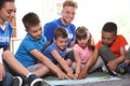 Young volunteers reading with children on floor indoors