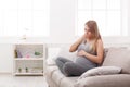 Young vomiting woman sitting on sofa
