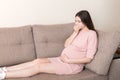 Young vomiting woman sitting on sofa and suffering with nausea. Pregnancy expectation concept, copy space