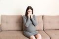 Young vomiting woman sitting on sofa and suffering with nausea. Pregnancy expectation concept, copy space Royalty Free Stock Photo