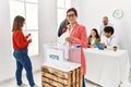 Young voter man smiling happy putting ballot in voting box at vote center