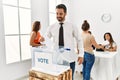 Young voter man smiling happy putting vote in voting box standing by ballot at electoral center Royalty Free Stock Photo