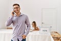 Young voter man talking on the smartphone standing by electoral table at vote center Royalty Free Stock Photo