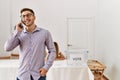 Young voter man talking on the smartphone standing by electoral table at vote center Royalty Free Stock Photo