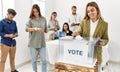 Young voter woman smiling happy putting vote in voting box at electoral center