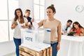 Young voter woman smiling happy putting vote in voting box standing by ballot at electoral center Royalty Free Stock Photo