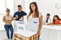 Young voter woman smiling happy putting vote in voting box standing by ballot at electoral center Royalty Free Stock Photo