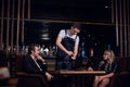 A young waiter guy opens a bottle of wine at the table in a restaurant Royalty Free Stock Photo