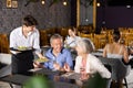 Young waiter serving ordered dishes to senior couple in restaurant Royalty Free Stock Photo