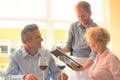 Young waiter showing menu to mature couple at restaurant