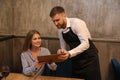 Young waiter showing woman a menu in restaurant