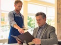 Young waiter taking orders from customer at restaurant