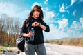 A young waiting caucasian woman looks at her wristwatch. Countryside road on the background. The concept of waiting